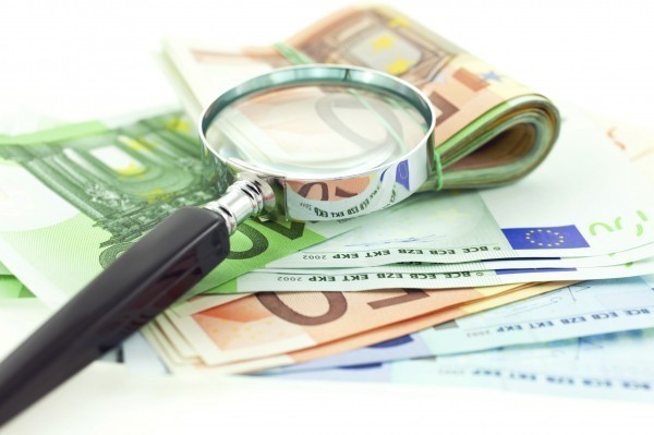 euro notes with magnifier on white background